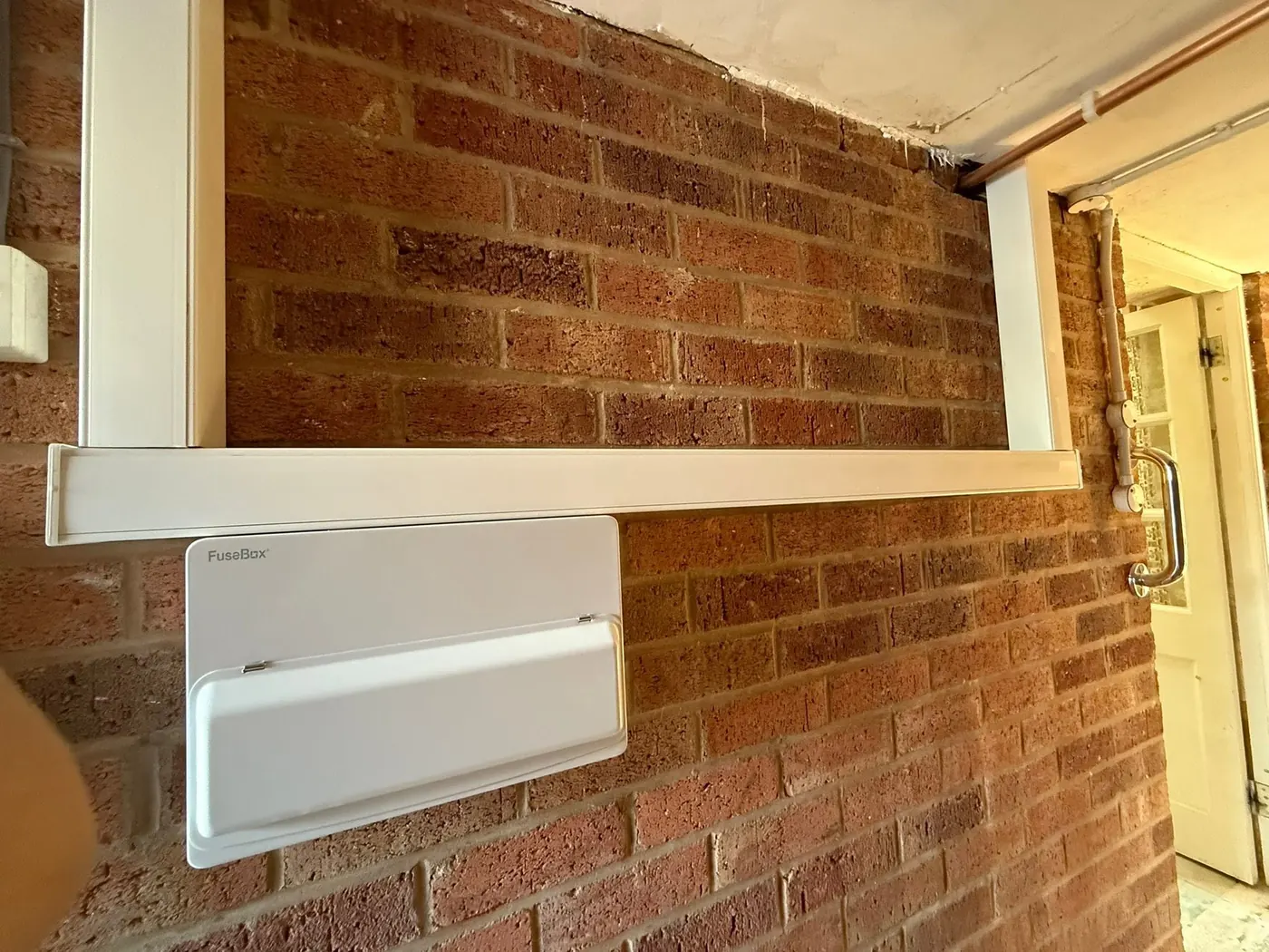 Consumer unit mounted on a brick garage wall with trunking run neatly above it