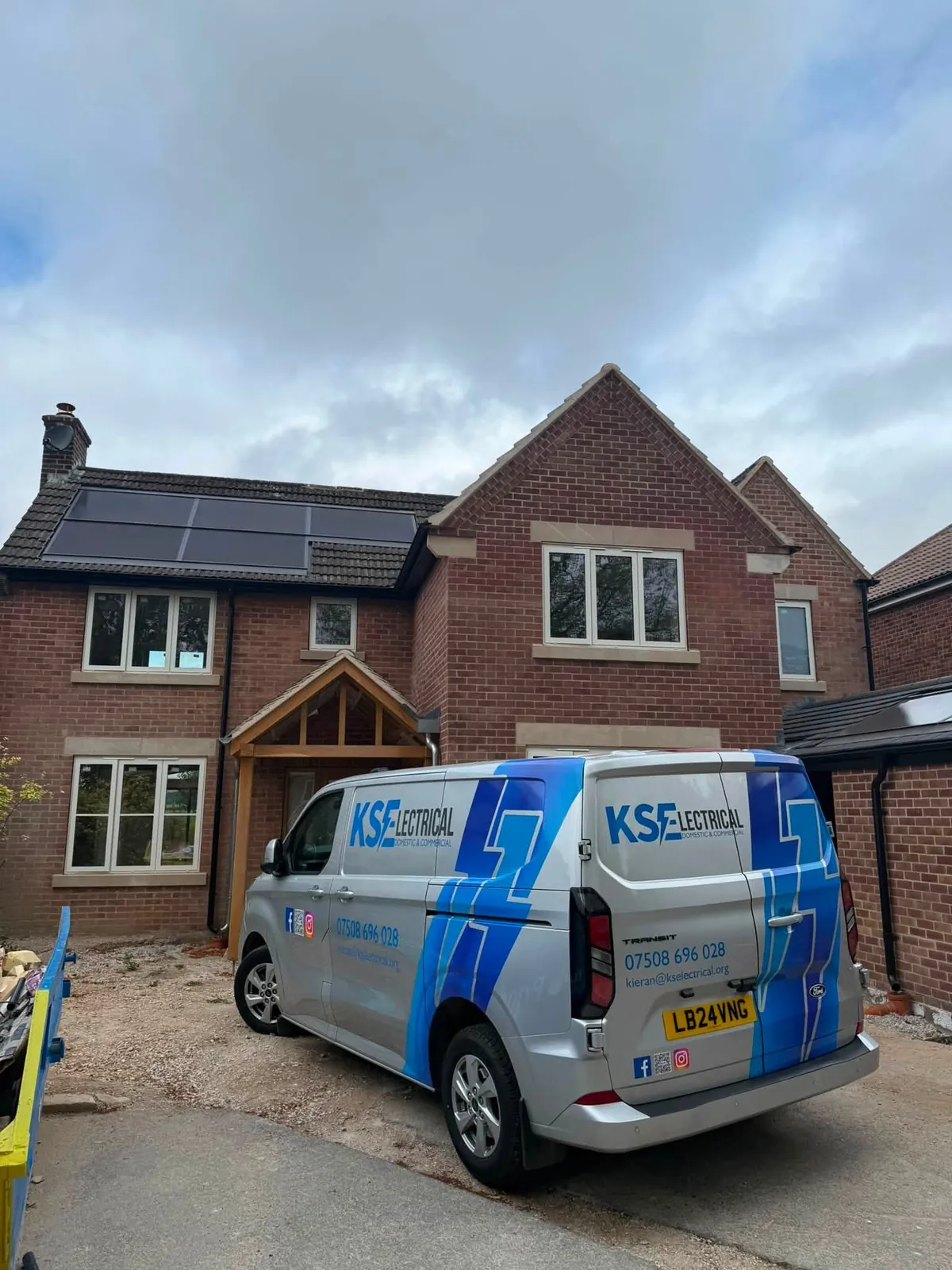 The KS Electrical van parked outside a newly built detached house with solar panels on the roof